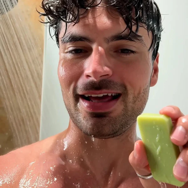 Man holding a Cougex cleansing bar in the shower
